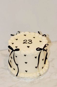 a white cake with black hearts on it and the number twenty eight in the middle