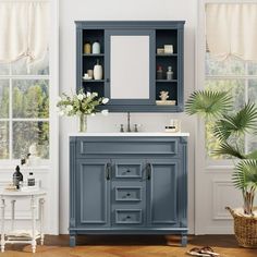 a bathroom with a blue cabinet, sink and potted plant in the corner next to it