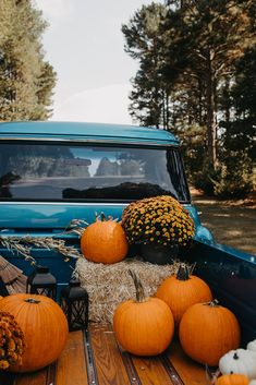 pumpkins and hay bales in the back of an old pickup truck parked on a road