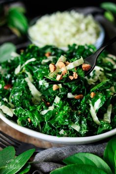 a bowl filled with greens and nuts on top of a table