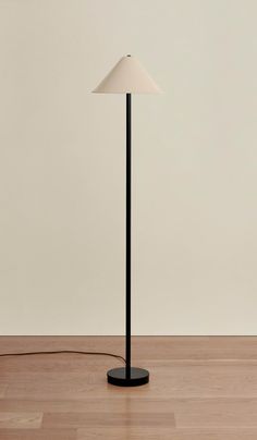 a floor lamp sitting on top of a hard wood floor next to a white wall