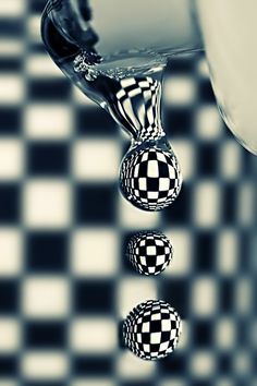 three balls floating in water on a black and white checkered surface