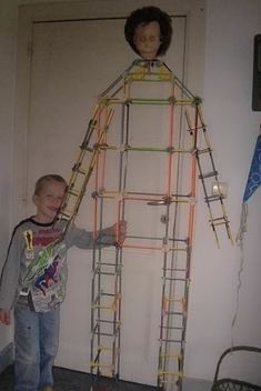 a young boy standing in front of a house made out of construction materials