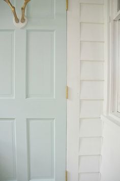 a white door with a deer antlers head hanging on it's side next to a window