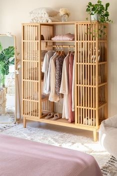 an open bamboo closet with clothes hanging on the rack and shoes sitting on the floor