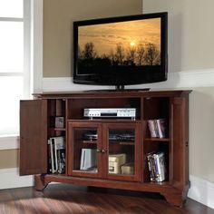 a flat screen tv sitting on top of a wooden entertainment center next to a window