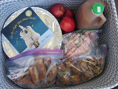 a basket full of food including apples, cheese and crackers