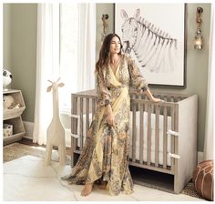 a woman standing in front of a crib with a zebra painting on the wall