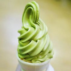 a cup filled with green frosting on top of a table