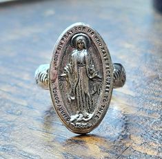 I converted a vintage Miraculous Medal into a pretty & comfortable ring... the traditional Miraculous Medal measures 22x13mm, the ring is a size 5 & 1/2.   I've kept all the beautiful traditional imagery on the back of the Miraculous Medal where it can rest against your skin. This ring is solid sterling silver, stamped Sterling on the inside. I go to estate sales and I love to purchase vintage or antique religious medals whenever I see them - it's fascinating to feel the smooth surfaces & wonder about how often it's been prayed over or blessed...often the top loop has worn away over time, so I like to make these into finger rings so they can be reborn into another life... ~ gift box included! Faith Jewelry, Sainte Marie, Miraculous Medal, Finger Rings, Catholic Faith, Estate Sales, Ring Vintage, Vintage Rings, Bathing Beauties