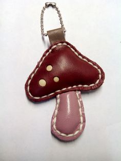 a red and white leather key chain with a mushroom shaped object hanging from it's side