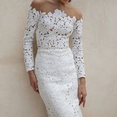 a woman wearing a white lace dress with off the shoulder sleeves and an open back