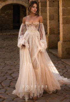 a woman in a long dress standing on a cobblestone street wearing an off the shoulder gown