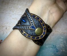 "\"Sapphire night\" is a tooled leather bracelet with shiny blue labradorite cabochon and metallic sheen. It would become a beautiful bright spot on your wrist. The bracelet fits up to 7\" (~17cm) wrist. The bracelet on the pictures is a sample, for it was MADE TO ORDER. You may place a custom order and I will make a new bracelet for you in accordance with desired measurements and preferred color palette. You may also choose a different gem - I've got plenty in stock, different colors and shapes Blue Wearable Art Jewelry For Festival, Blue Leather Bracelets For Festival, Blue Leather Jewelry For Festivals, Blue Leather Festival Bracelets, Blue Adjustable Hand Tooled Jewelry, Handmade Blue Leather Festival Bracelet, Handmade Blue Leather Bracelet For Festival, Adjustable Hand Tooled Blue Jewelry, Adjustable Blue Patina Cuff Bracelet