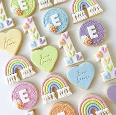 decorated cookies with rainbows, hearts, and love letters on a white table top