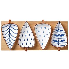 three blue and white plates hanging on a wooden wall with hooks in the shape of leaves