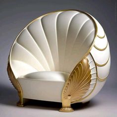 a white chair with gold accents and a shell shaped seat on the back, in front of a gray background