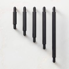 four black pens are lined up on a white surface, with one pen in the middle