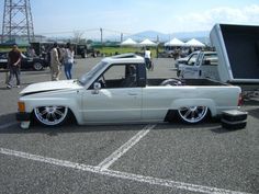 a white pick up truck parked in a parking lot next to other cars and people