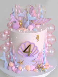 a pink and blue birthday cake with mermaid decorations