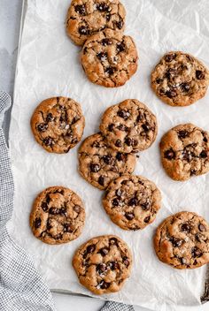 several chocolate chip cookies on top of a piece of parchment paper