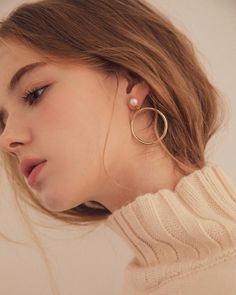 a woman wearing large hoop earrings and a sweater