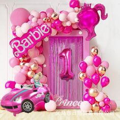 a pink car is parked in front of a balloon arch with the number one on it