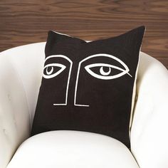 a black and white pillow with an eye drawn on the front, sitting on a chair