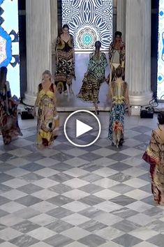 several women are walking down the runway at a fashion show in front of an ornate building