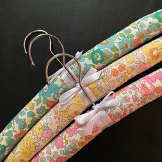 four colorful umbrellas with bows tied to them on a black background, one has a white bow and the other has flowers