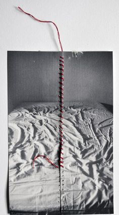 an open book with red string attached to the cover and on top of a bed