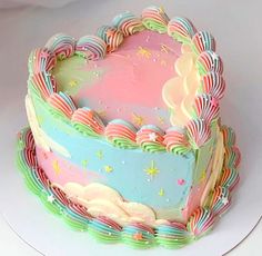 a heart shaped cake sitting on top of a white plate with pink and blue frosting