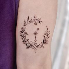 a woman's arm with a clock and flowers tattoo on the left side of her arm