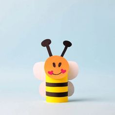 a yellow and black toy with a bee on it's back, sitting in front of a blue background