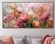 a painting on the wall above a couch in a living room with pink and yellow flowers