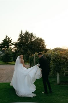 a bride and groom standing in the grass