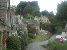 an image of a street with houses on the side and cars parked along the road