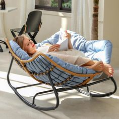 a woman laying in a hammock reading a book while sitting on a chair