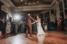 a bride and groom dancing on the dance floor at their wedding reception in front of an audience