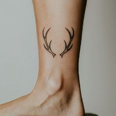 a small tattoo on the ankle of a woman's foot with antelope horns