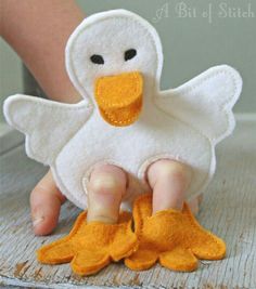 a white duck with yellow feet is sitting on the floor next to someone's hand