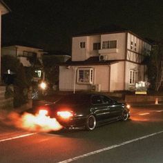 a black car with flames coming out of it's hood on the street at night