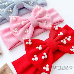 four bows with pearls on them sitting next to each other in different colors and sizes