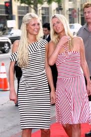 two women in striped dresses walking down the red carpet with one woman holding her hand