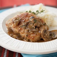 a white plate topped with meat covered in mushroom gravy