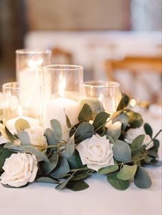 candles and flowers on a table with greenery