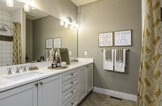 a bathroom with two sinks, mirrors and towels hanging on the wall in front of it