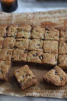 chocolate chip cookie bars cut into squares on top of a piece of parchment paper next to a glass of orange juice