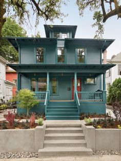 a blue house with stairs leading up to the front door