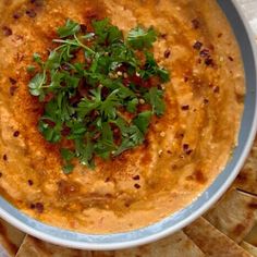 a white bowl filled with hummus and garnished with parsley on top